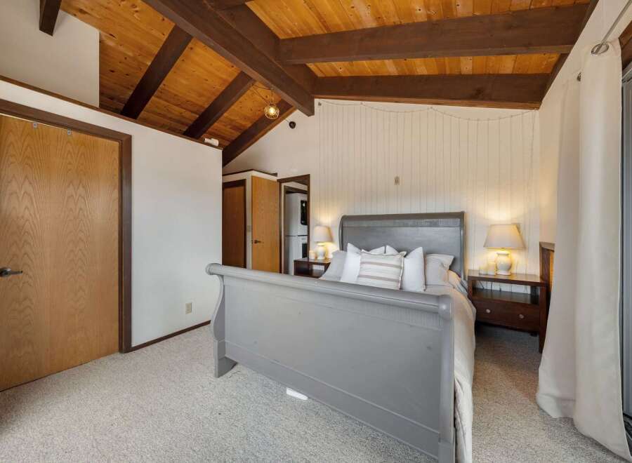 This stunning bedroom boasts a unique wooden ceiling with exposed beams, creating a warm and inviting atmosphere.