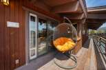 Relax and unwind in this stunning outdoor space! Featuring a cozy hanging chair with a vibrant orange cushion, this area is perfect for enjoying the fresh air and sunshine.