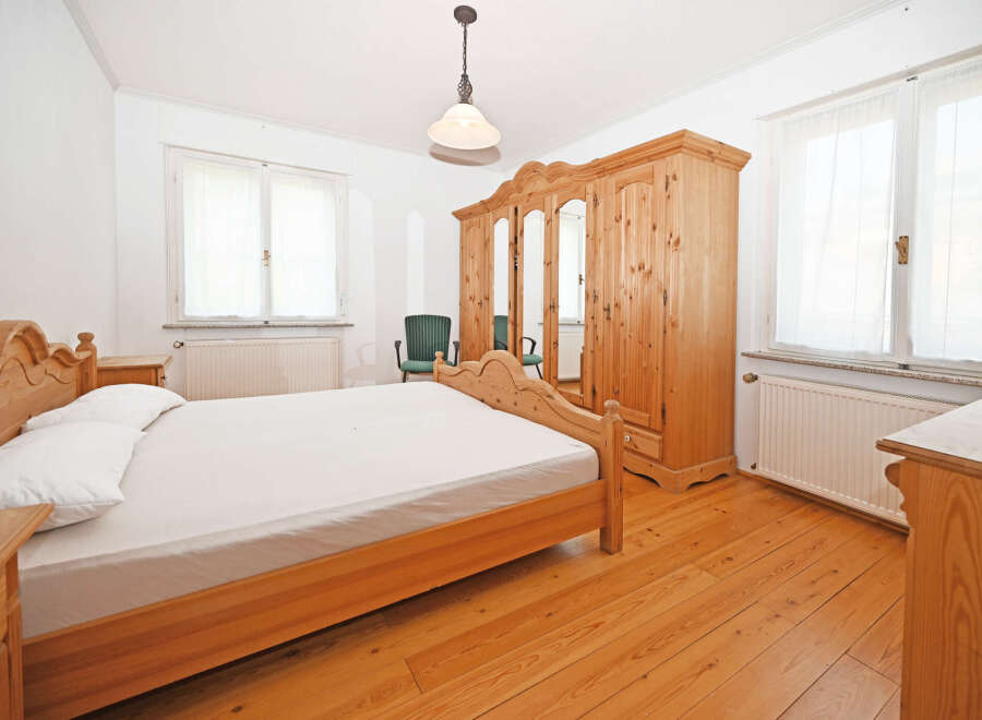 This charming bedroom features a warm, inviting atmosphere with its wooden furniture and flooring.