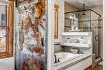 Step into luxury with this stunning bathroom featuring a unique, rustic metal door that adds a touch of industrial charm.