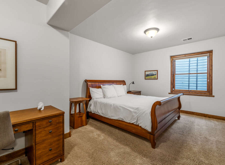 This cozy bedroom features a beautiful wooden bed frame and a comfortable, inviting atmosphere.