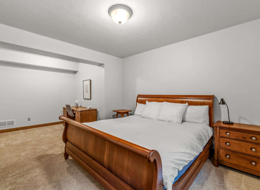 This inviting bedroom features a classic wooden bed frame, offering a warm and traditional aesthetic.