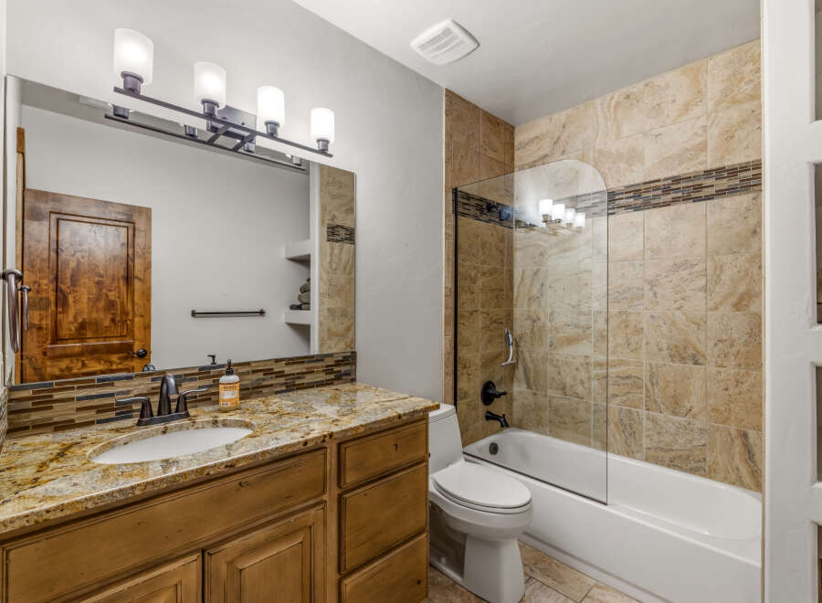 This stunning bathroom boasts a luxurious design with a granite countertop and a stylish vanity.