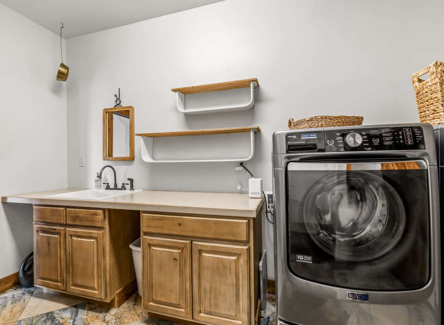 This laundry room features a modern design with a Maytag washing machine and ample counter space.
