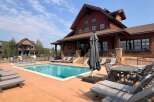 Enjoy luxurious living at this stunning property featuring a beautiful outdoor pool and a charming, rustic-style building.