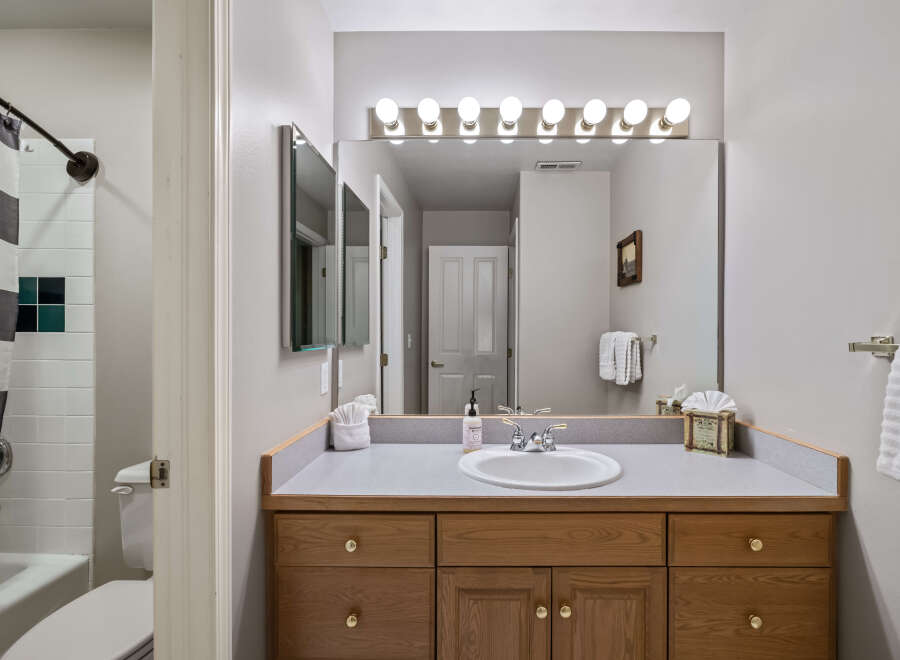 This inviting bathroom features a well-lit vanity area with a large mirror and ample storage.