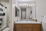 This inviting bathroom features a well-lit vanity area with a large mirror and ample storage.