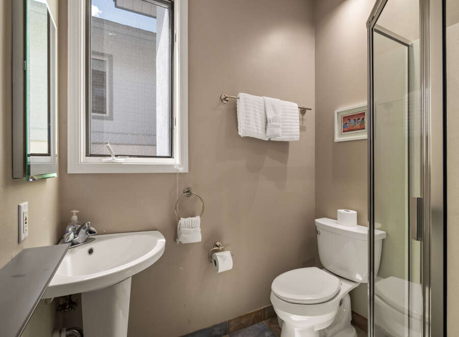 This bathroom features a modern design with a pedestal sink and a sleek glass shower enclosure.