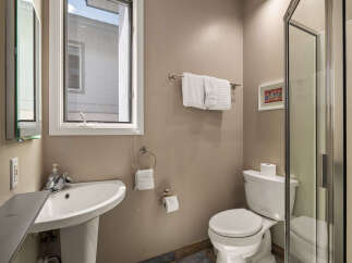 This bathroom features a modern design with a pedestal sink and a sleek glass shower enclosure.