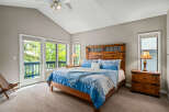 This stunning bedroom boasts a vaulted ceiling and ample natural light, creating a bright and airy atmosphere.