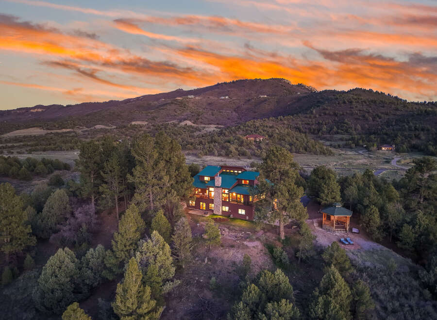 Nestled in a serene mountain setting, this stunning property boasts a luxurious home with a distinctive green roof.