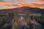 Nestled in a serene mountain setting, this stunning property boasts a luxurious home with a distinctive green roof.