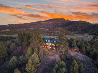 Nestled in a serene mountain setting, this stunning property boasts a luxurious home with a distinctive green roof.