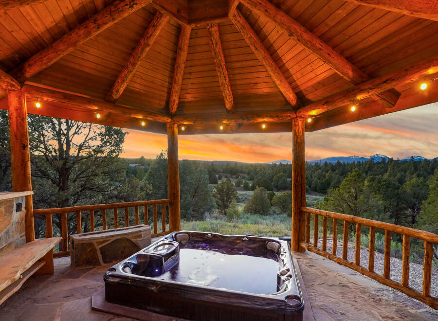 Relax and unwind in this stunning outdoor oasis! This property features a luxurious hot tub nestled under a beautiful wooden gazebo, perfect for enjoying the breathtaking sunset views.