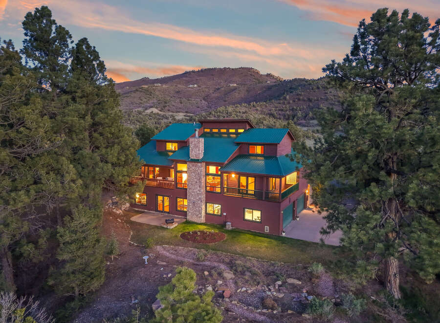 Nestled in a serene mountain setting, this stunning property boasts a luxurious multi-story home with a striking green roof.