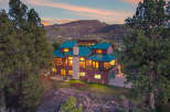 Nestled in a serene mountain setting, this stunning property boasts a luxurious multi-story home with a striking green roof.