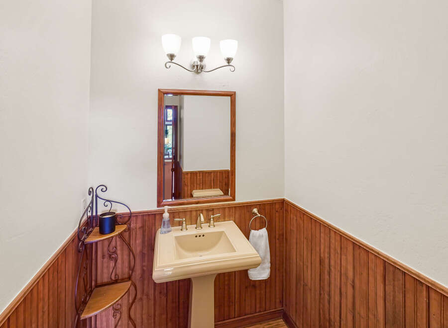 This charming powder room features a classic pedestal sink and a beautiful wooden accent wall.