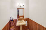 This charming powder room features a classic pedestal sink and a beautiful wooden accent wall.