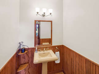 This charming powder room features a classic pedestal sink and a beautiful wooden accent wall.
