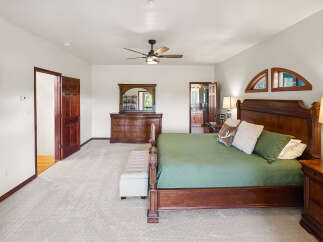 Step into this elegant master bedroom, featuring a luxurious king-sized bed with a rich, wooden frame and a serene green comforter.