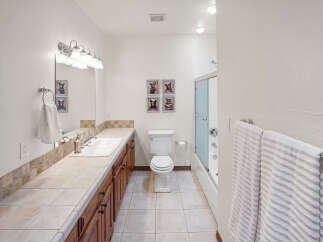 Step into this inviting bathroom, featuring a well-lit vanity area with a large mirror and ample counter space.