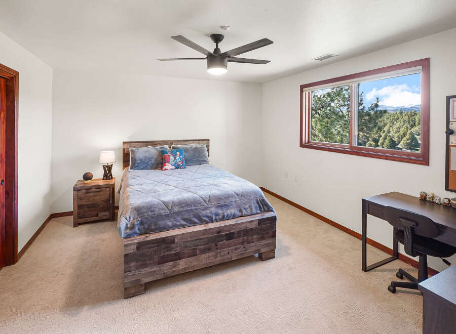 This inviting bedroom features a rustic wooden bed frame and a cozy, neutral carpet, creating a warm and comfortable atmosphere.