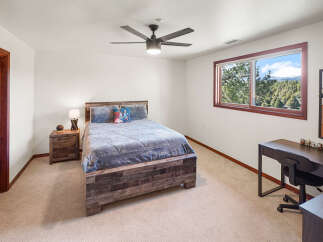 This inviting bedroom features a rustic wooden bed frame and a cozy, neutral carpet, creating a warm and comfortable atmosphere.