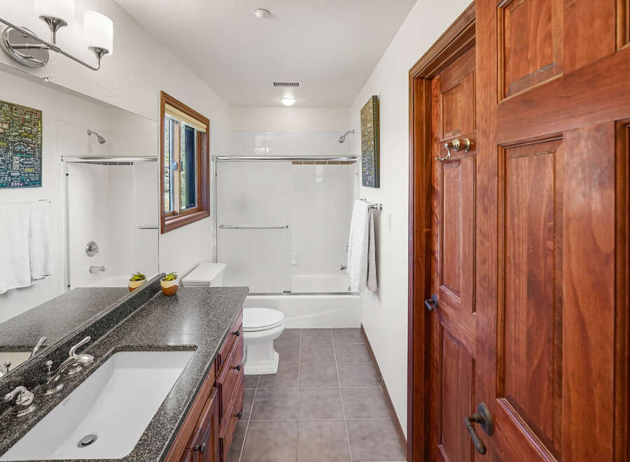 Step into this inviting bathroom, featuring a sleek vanity with a dark countertop and a pristine white sink.