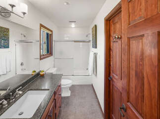 Step into this inviting bathroom, featuring a sleek vanity with a dark countertop and a pristine white sink.