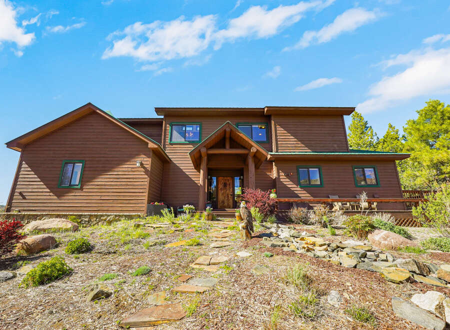 Nestled amidst nature's embrace, this stunning property boasts a rustic charm with its wooden exterior and inviting entrance.