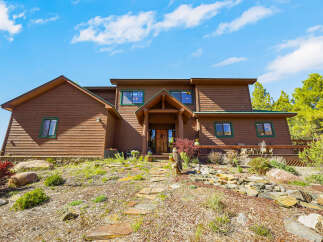 Nestled amidst nature's embrace, this stunning property boasts a rustic charm with its wooden exterior and inviting entrance.