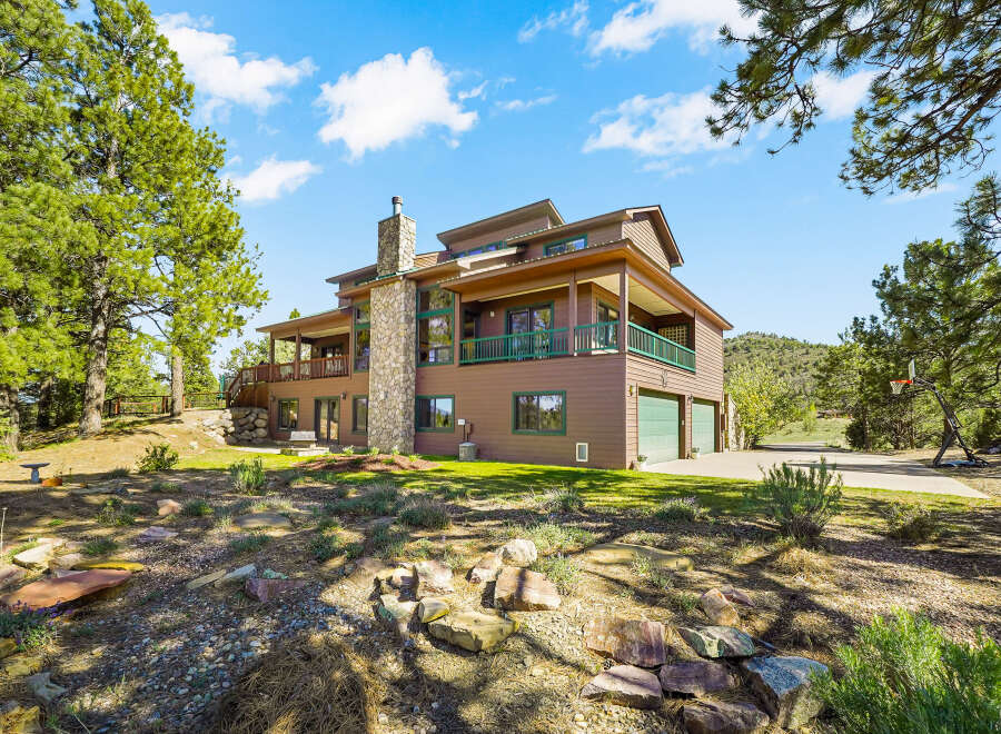 This stunning property boasts a spacious multi-level home with a beautiful stone chimney and a charming wooden deck.