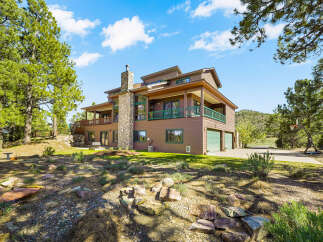 This stunning property boasts a spacious multi-level home with a beautiful stone chimney and a charming wooden deck.