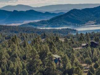 Nestled amidst a lush forest, this property offers breathtaking views of a serene lake and rolling mountains.
