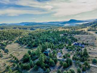 Discover your private oasis with this stunning aerial view of a sprawling property nestled amidst a dense forest.