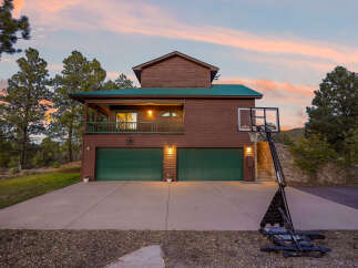 Experience rustic charm with this beautiful wooden home, featuring a durable green metal roof and a spacious two-car garage.