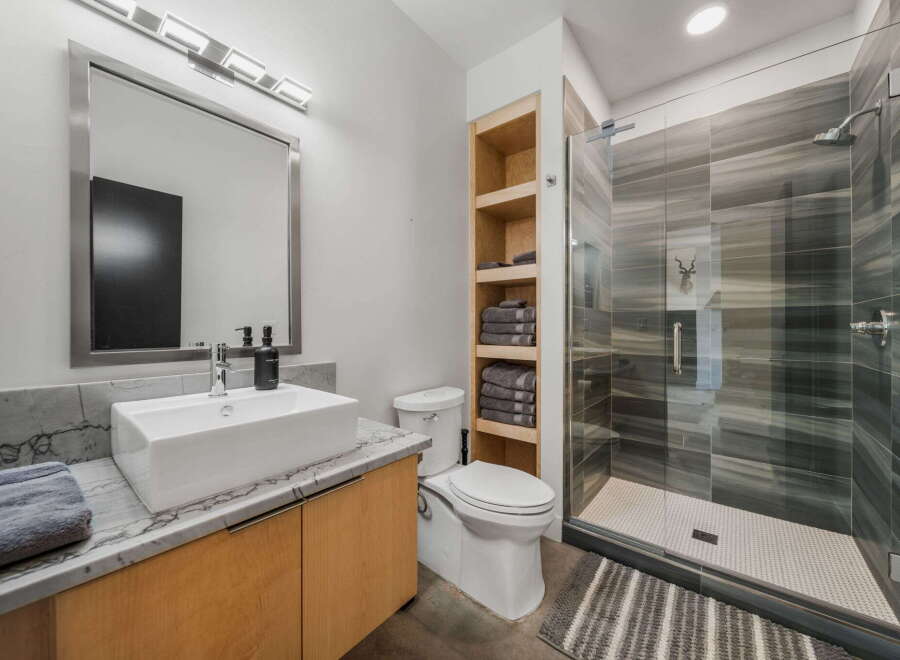 Step into a modern bathroom oasis! This stunning space features a sleek vanity with a marble countertop, a contemporary vessel sink, and a large mirror.