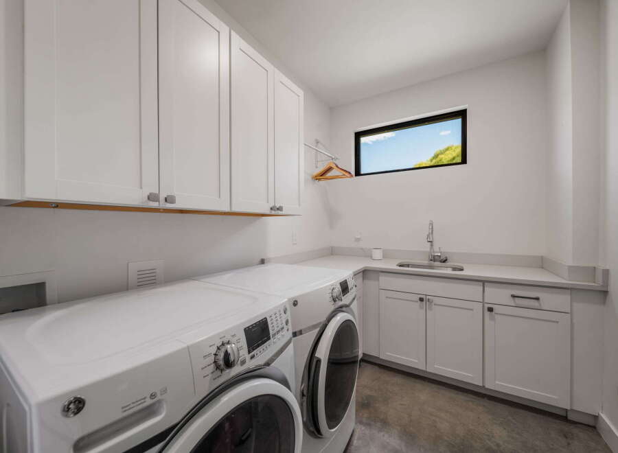 This modern laundry room boasts sleek white cabinetry and a convenient countertop, perfect for folding and organizing.