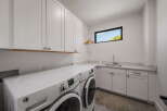 This modern laundry room boasts sleek white cabinetry and a convenient countertop, perfect for folding and organizing.