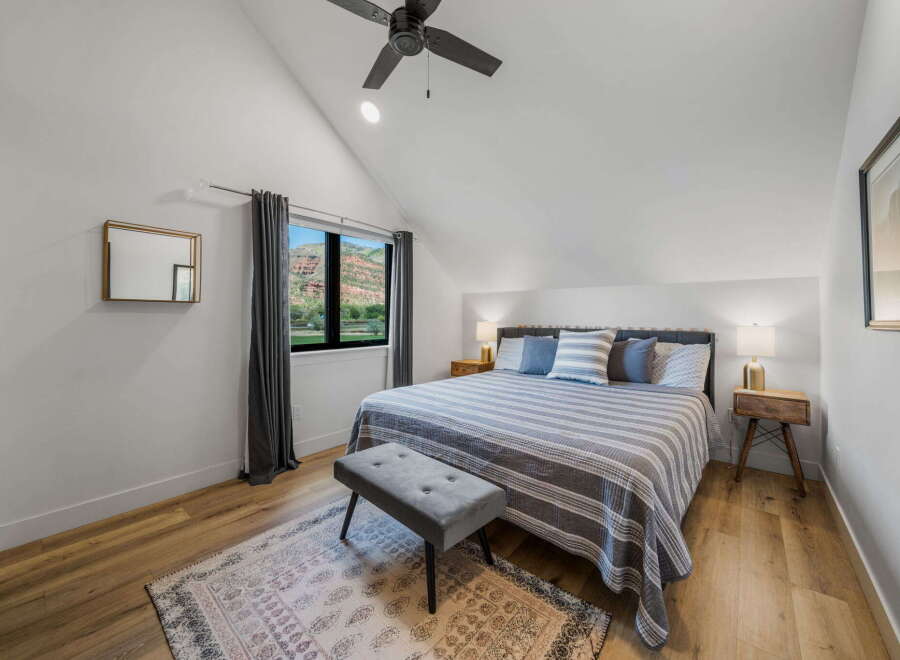 This stunning bedroom boasts a modern design with a vaulted ceiling and ample natural light.