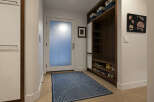 Step into this inviting entryway, showcasing a modern design with a built-in storage unit and a stylish blue rug.