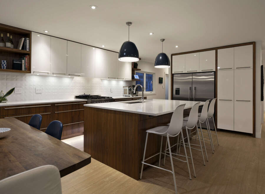 This stunning kitchen boasts modern design with sleek white cabinetry and warm wood accents.