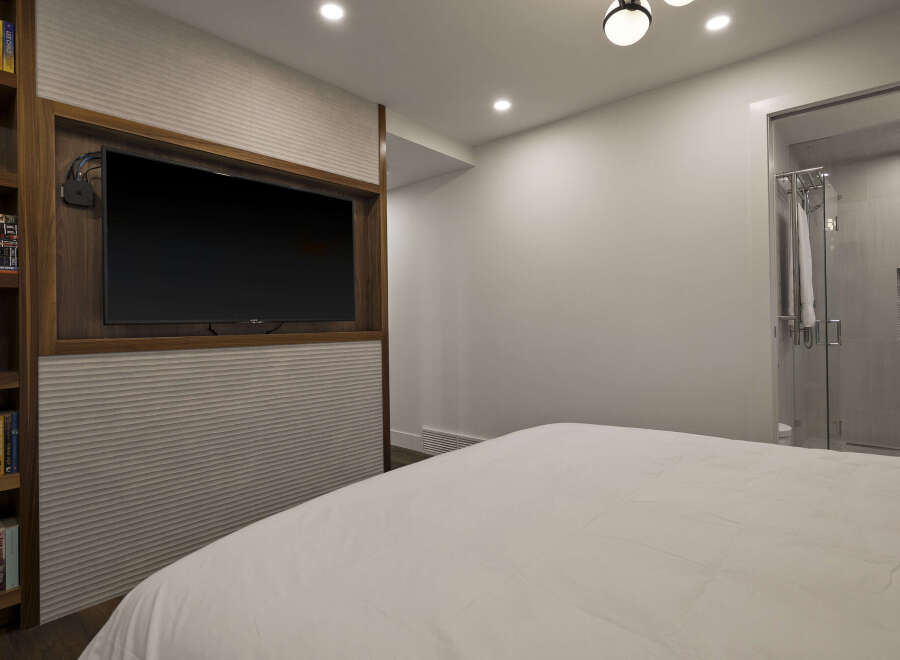 This modern bedroom features a sleek design with a built-in entertainment center, perfect for relaxing.