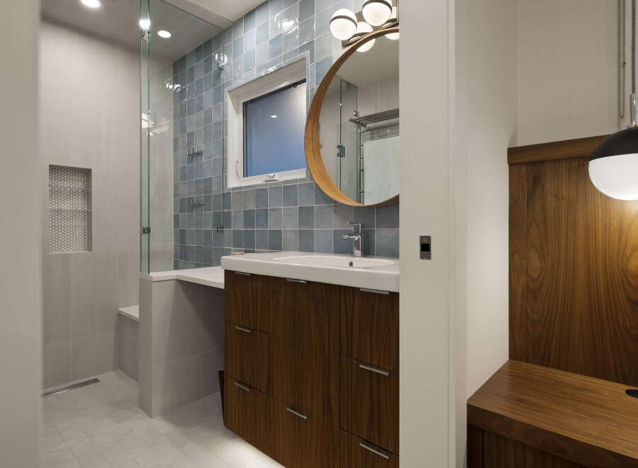 Step into a modern bathroom oasis, featuring a sleek vanity with ample storage and a stylish round mirror.
