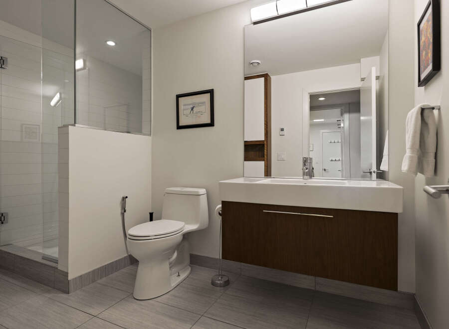 This modern bathroom features a sleek design with a glass-enclosed shower and a floating vanity.