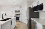 Step into this stunning kitchen, boasting modern white cabinetry and sleek black hardware.