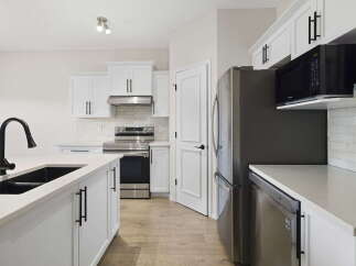 Step into this stunning kitchen, boasting modern white cabinetry and sleek black hardware.