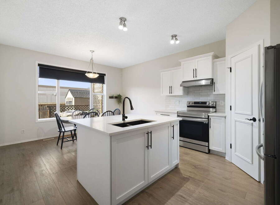 This stunning kitchen boasts a modern design with sleek white cabinetry and a spacious island, perfect for meal preparation and entertaining.