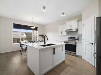 This stunning kitchen boasts a modern design with sleek white cabinetry and a spacious island, perfect for meal preparation and entertaining.