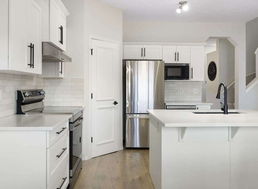 This stunning kitchen boasts modern design with sleek white cabinetry and stainless steel appliances.